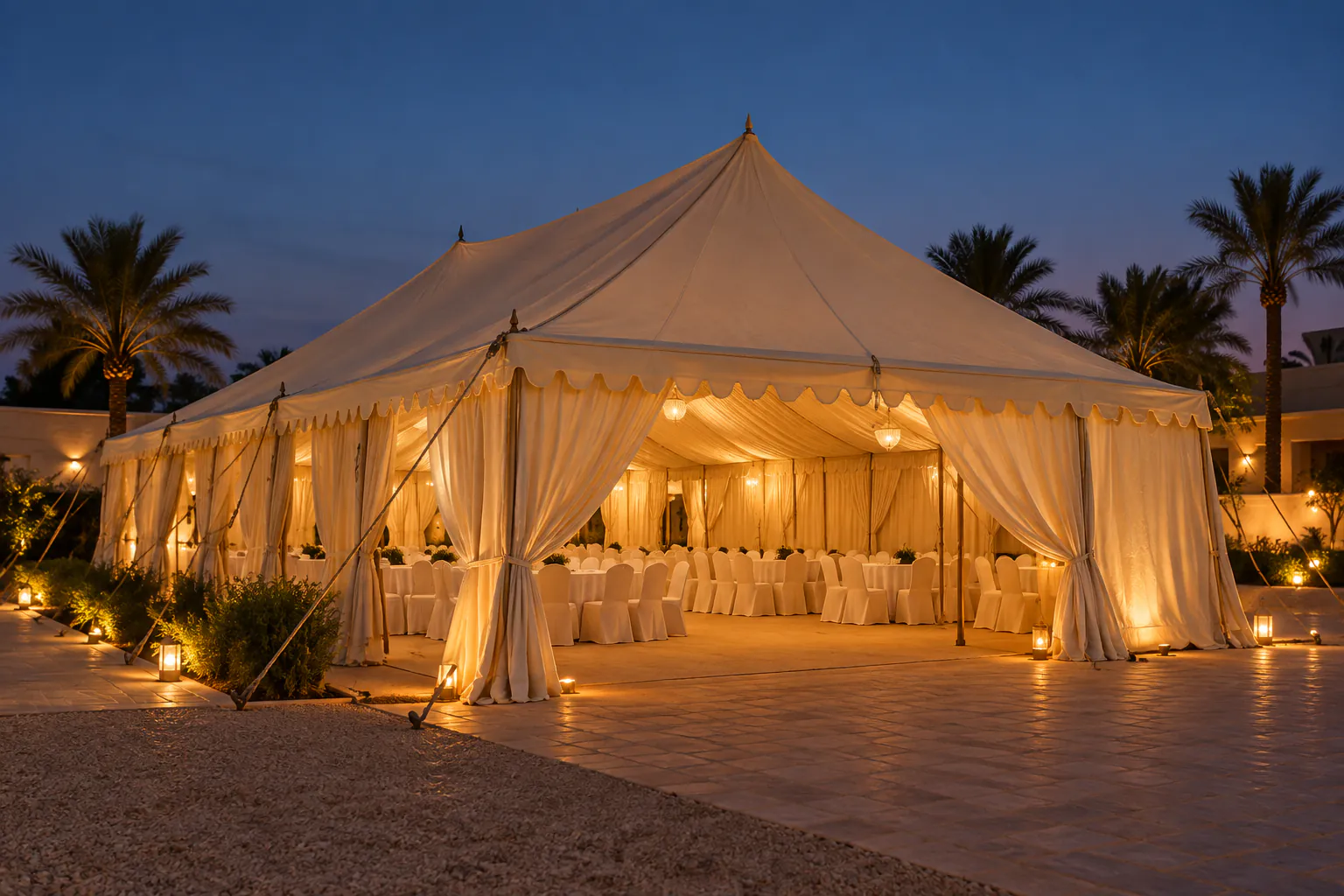 Large white tent lit at night with covered tables and chairs inside